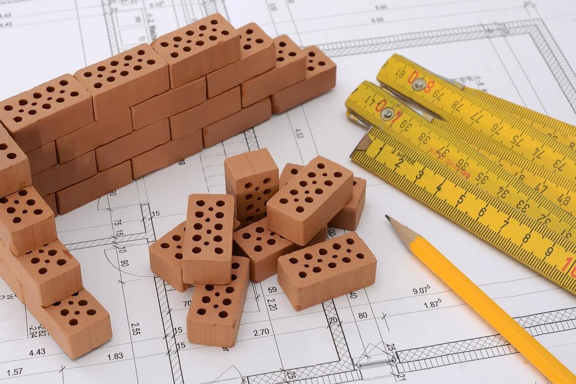 piccoli mattoncini sopra un progetto con a fianco matita e metro
